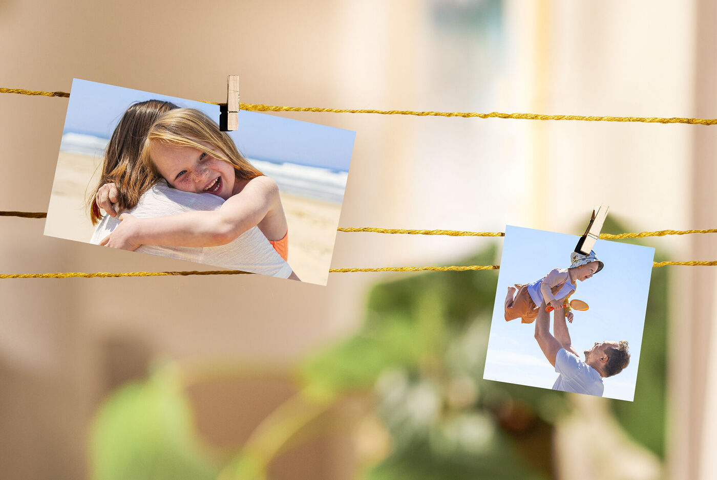 Zwei Fotos an einer Schnur aufgehängt, eines zeigt eine Umarmung am Strand, das andere eine Person, die ein Kind hochhält